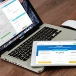 Close-up of a laptop and tablet on a wooden desk, showcasing modern technology.